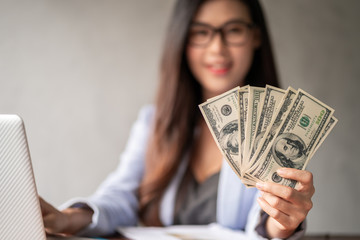 Dollar in a businesswoman hand. A Asia woman is working from home or office and glad to get dollar money from work and from a supplementary career or Part-time self-employment.