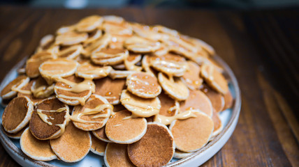 A plate of Dutch Mini Pancakes, poffertjes with peanut butter on the wooden background