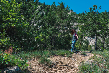 Obraz premium A full body shot of a young Caucasian female hiker with a backpack walking down a path in the French Alps mountains on a sunny summer day