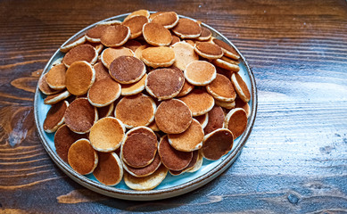 Freshly baked a plate of poffertjes, traditional Dutch Mini Pancakes without any other ingredients with the wooden background