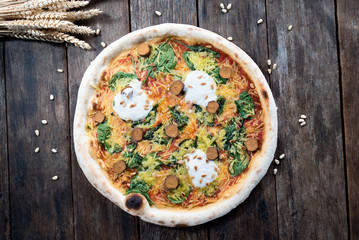 An beautiful vegan pizza with a nice old wooden table with wheat and pine nuts next to it, ideal for designing text around 
