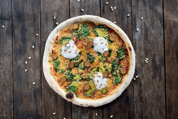 An isolated amazing vegan styled pizza with a nice old wooden table and pine nuts around, ideal for designing text around
