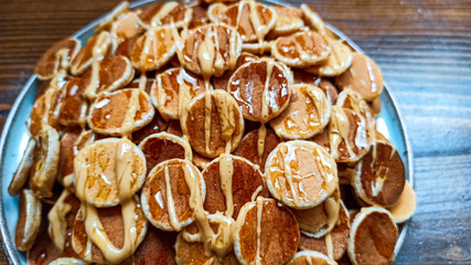 Obraz na płótnie Canvas A plate of poffertjes with peanut butter and honey on the wooden background. Dutch mini pancakes ready for breakfast