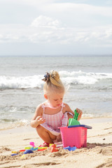 Summer vacation. Adorable toddler girl playing with beach toys on the sandy beach.