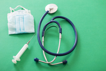 medical mask and stethoscope on green background