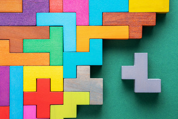 Different colorful shapes wooden blocks on green background, flat lay.