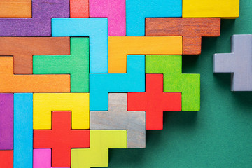 Obraz premium Different colorful shapes wooden blocks on green background, flat lay.