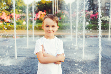Portrait of happy boy over fountain background. Summer vacation, lifestyle.