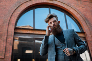 guy in a suit and with a cigarette on a background of a brick building