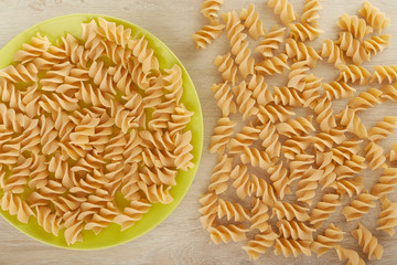 Raw pasta on a green plate, top view