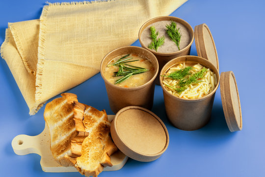 Pea, Mushroom and chicken soup in paper disposable cups for take-out or delivery of food on blue background.