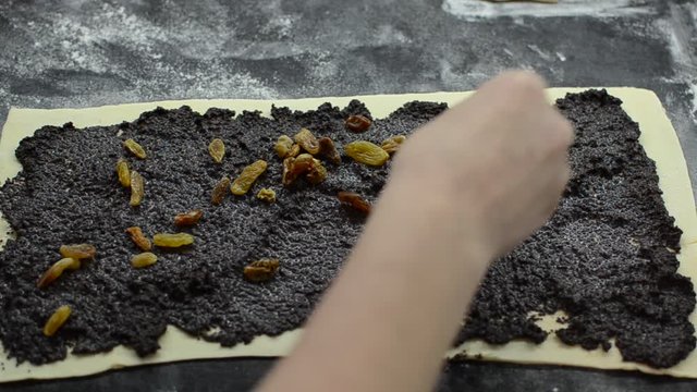 Cook puts grape raisins on raw dough with poppy seeds