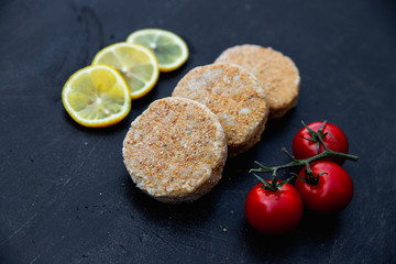 Raw cutlets on black background