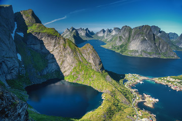 Reine, Lofoten, Norway. The village of Reine under a sunny, blue sky, with the typical rorbu houses. View from the top of Reinebringen mountain. - obrazy, fototapety, plakaty