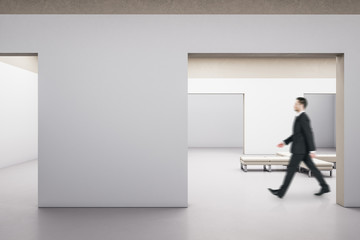 Fototapeta premium Businessman walking in exhibition interior with bench.