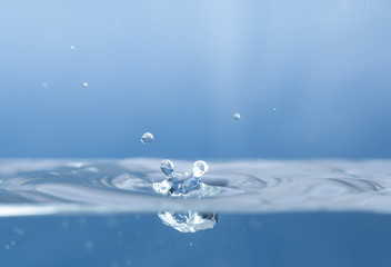 Water drops splash and circle reflextion background.Close up rain drops falling into the water and ripples of light blue.