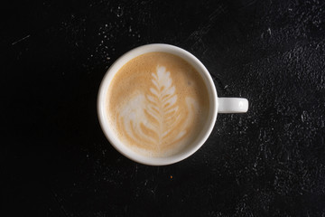 Classic pattern on milk froth in a cup with cappuccino. White cup with cappuccino top view.