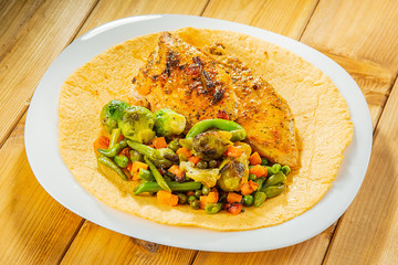 Grilled chicken breast and a mixture of vegetables on a corn tortilla in a white plate. Close-up