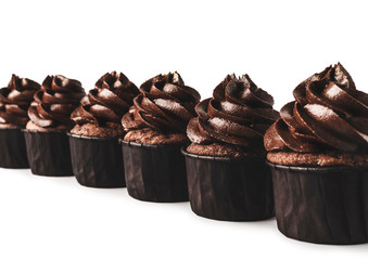 Delicious chocolate cupcakes with gold sparkles sprinkled on chocolate icing lined up diagonaly on isolated white background. Mockup for your design. Close-up. Place for text.