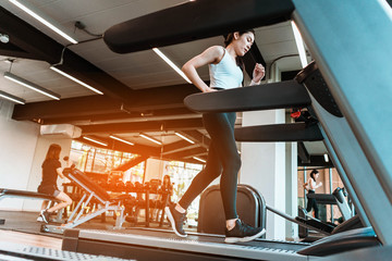 Fototapeta na wymiar young sports woman is running treadmill in gym. Doing cardio training