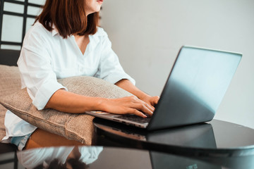 young woman working on laptop computer while sitting at the living room. work from home concept