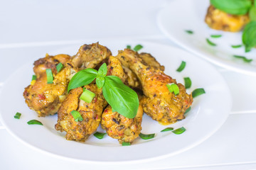fried chicken with greens on a white plate close-up. pieces of cooked chicken and a sprig of basil.