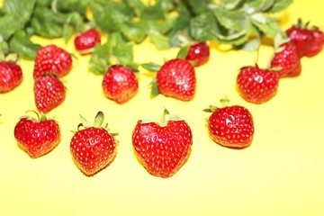 Strawberry berries with mint isolated on a yellow background. Strawberries and mint leaves on a bright yellow background. Background for the design of banners, websites, blogs. Copy space. Red berries