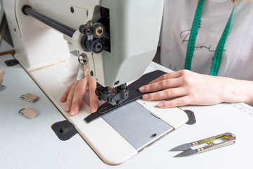 girl sews on a sewing machine scribbles fabric and leather making a product