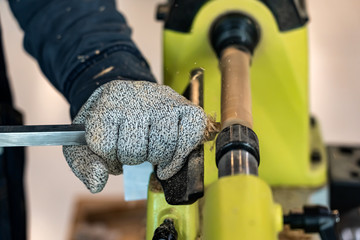 Carpenter man is carving the wooden stick. Spinning wood wheel machine. Trimming forming a round detail. Joiner is using metal tool to make the handmade decoration at workshop.