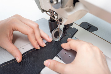 girl sews on a sewing machine scribbles fabric and leather making a product