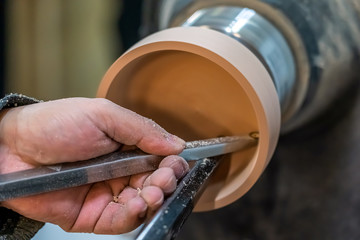 Carpenter man is shaving the wooden bowl. Spinning wood wheel. Carving inside forming a round...