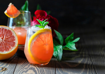 A glass of freshly squeezed grapefruit juice and mint on a dark wooden table. Refreshing summer cocktail.