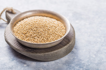 Raw  white  quinoa seeds (lat. Chenopodium quinoa) on  plate with wooden spoon