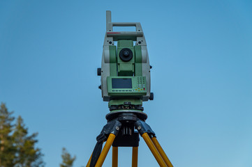Surveyors equipment (theodolite or total positioning station) on the construction site of the road or building with construction machinery background