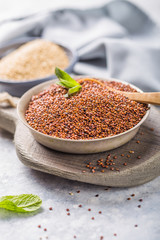 Raw  red and white  quinoa seeds (lat. Chenopodium quinoa) on  plate with wooden spoon