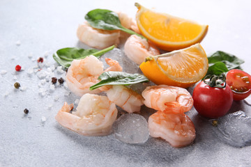 Seafood. Raw pink prawns shrimp with lemon, herbs, spices, ice and cherry tomato on a light grey background. Background image, copy space
