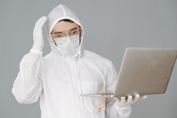 Corona virus theme. Man in a protective suit. Doctor use a laptop.