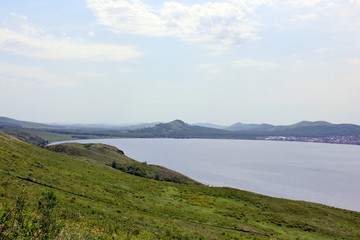 Great panoramic view. A clean mountain lake in the midst of majestic mountains in a haze