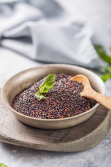 Raw  black quinoa seeds (lat. Chenopodium quinoa) on  plate with wooden spoon