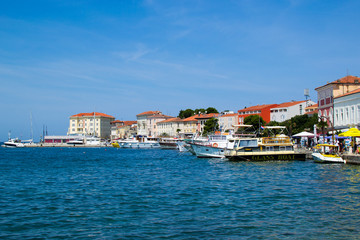 Fototapeta na wymiar Porec (Parenzo), Croatia; 7/19/19: View of the typical croatian houses in the coastline of the old town of Porec (also called Parenzo), Croatia, with boats anchored on the port in Adriatic Sea