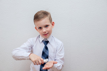 A boy in a white shirt is treating his hands with alcohol disinfectant.