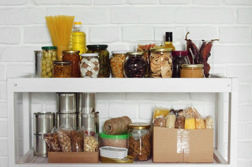 Set of long storage term foods on pantry shelf prepared for disaster emergency conditions on brick...