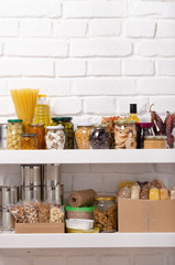 Set of long storage term foods on pantry shelf prepared for disaster emergency conditions on brick wall background - obrazy, fototapety, plakaty