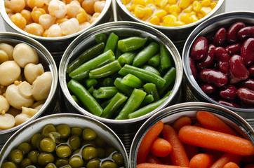 Canned vegetables in opened tin cans on kitchen table. Non-perishable long shelf life foods...