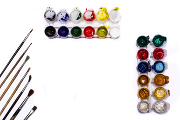 jars of gouache and paint brushes on a white background with a copy of the space