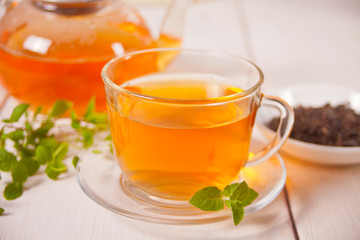 Cup of fresh green or black tea with mint on the white wooden table. Detox and antioxidant drink.