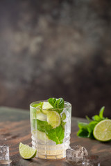 Mojito cocktail with lime and mint in glass on a grey background