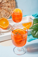 Glasses with fresh homemade orange sweet iced tea or cocktail, lemonade with thyme. Refreshing cold drink. Summer party.