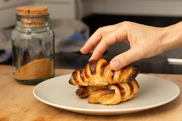 hand taking a freshly-baked homemade croissant from a plate