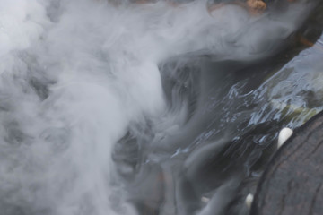 Defocused and blurred image for background. White steam,Hot Springs, Boiling and steaming water in geyser vent, Large stones arranged, Boiling water splash. closeup, vintage style.